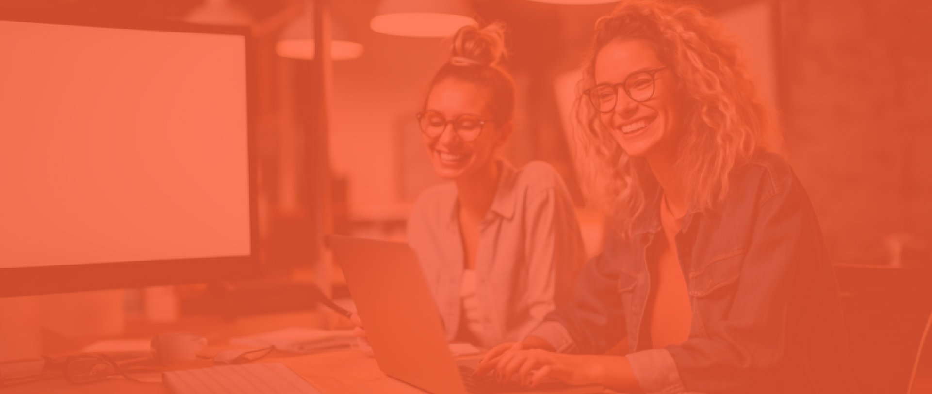 Two Women Smiling While Working with a Laptop